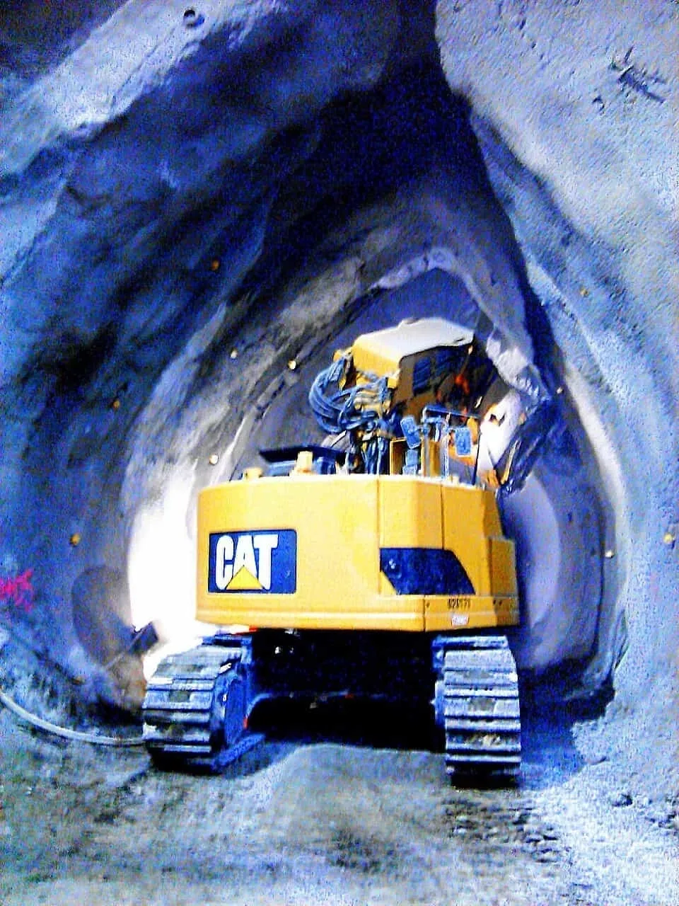 A yellow cat tractor in the middle of an underground tunnel.